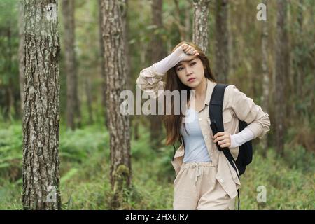 donna stanca che porta uno zaino viaggio e camminare nella foresta Foto Stock