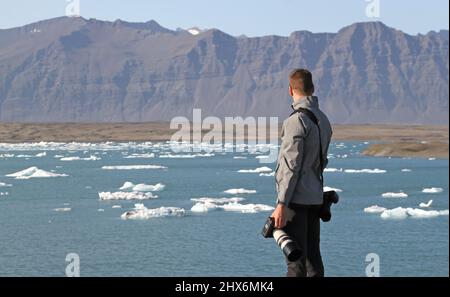 Uomo che domina la laguna del ghiacciaio Jokulsarlon nel sud dell'Islanda Foto Stock