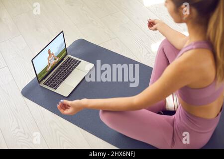 Donna che guarda una video lezione di meditazione o pratica di yoga con un insegnante online Foto Stock