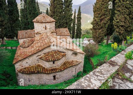 Greco ortodosso 11th secolo in pietra costruita chiesa con croce sopra la cupola. San Nicola circondato da cipressi a Karytaina, Arcadia Peloponneso. Foto Stock