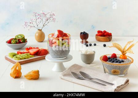 Vista ad angolo basso del dessert chia budino con bacche estive, fragole, kiwi e fette di cocco, impreziosito da un rametto di menta. Nessuna gente. Foto Stock