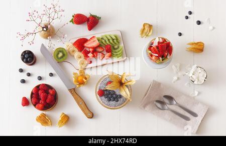 Vista ad angolo basso del dessert chia budino con bacche estive, fragole, kiwi e fette di cocco, impreziosito da un rametto di menta. Nessuna gente. Foto Stock