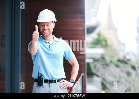 Sono stati tutti destinati ad andare. Ritratto di un ingegnere allegro che posava con i pollici fuori da un edificio. Foto Stock