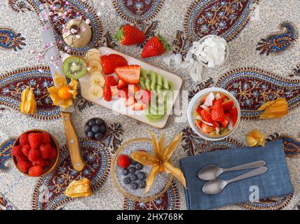 Vista ad angolo basso del dessert chia budino con bacche estive, fragole, kiwi e fette di cocco, impreziosito da un rametto di menta. Nessuna gente. Foto Stock