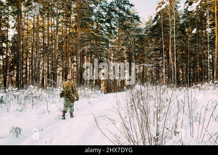 Soldato medico americano degli Stati Uniti fanteria della seconda guerra mondiale marciando lungo Forest Road nel giorno d'inverno Foto Stock