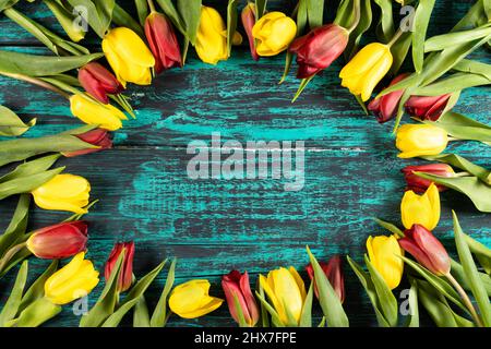 Una cornice di fiori primaverili di tulipani sullo sfondo di un bordo blu shabby. Uno sfondo fantastico per la tua foto design.Horizontal. Foto Stock