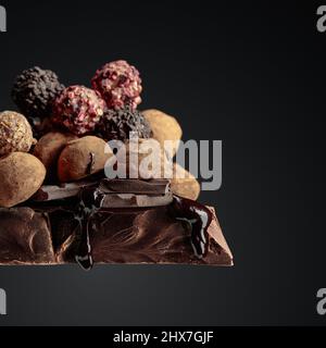 Tartufi di cioccolato e gocce di salsa di cioccolato su un grande pezzo di cioccolato fondente. Spazio di copia. Foto Stock