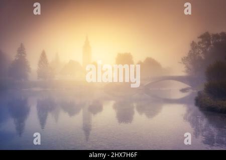 Maestoso e colorato giorno di nebbia sul lago nel parco nazionale del Triglav, situato nella valle di Bohinj delle Alpi Giulie. Vista spettacolare della chiesa di St. Foto Stock