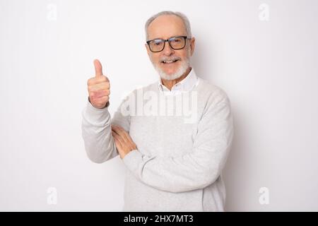 Bell'uomo anziano in maglione casual mostra pollice su isolato su sfondo bianco. Foto Stock