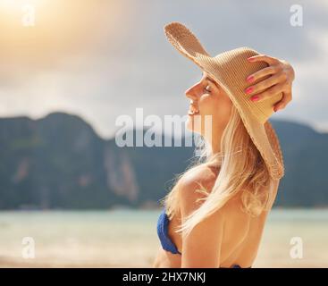 Crogiolarsi al sole. Scatto di una giovane donna felice in un bikini rilassante su una spiaggia tropicale. Foto Stock