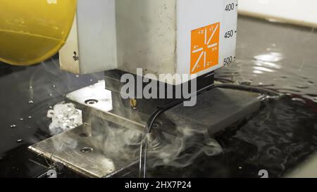 La macchina a getto d'acqua abrasiva taglia la piastra di alluminio. Scena. La moderna tecnologia del processo di lavorazione della lamiera mediante getto d'acqua ad alta pressione Foto Stock