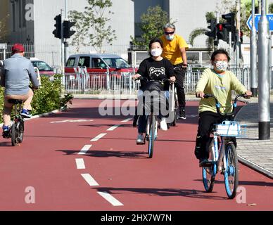 (220310) -- HONG KONG, 10 marzo 2022 (Xinhua) -- le persone che indossano maschere facciali cavalcano biciclette a Tsuen WAN, Hong Kong della Cina meridionale, 10 marzo 2022. La Regione amministrativa speciale di Hong Kong (HKSAR) ha segnalato 24.390 nuovi casi COVID-19 il 9 marzo. (Xinhua/lo Ping Fai) Foto Stock