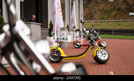 I ciclomotori sono in fila sul quadrato. Sparatutto colorati parcheggiati con bandiere attaccate a loro sulla piazza vicino all'edificio degli uffici Foto Stock