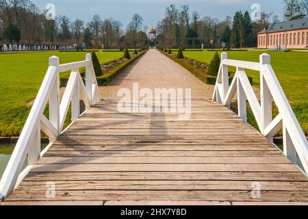 Un ponte di legno che conduce al passaggio pedonale del parterre orangeria nel giardino del famoso Palazzo di Schwetzingen con l'Apollopapel (tempio di... Foto Stock