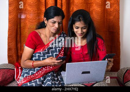 Madre e figlia adolescente che usano il telefono cellulare mentre osservano il taptop a casa - concetto di stile di vita tecnologico, la distazione dei social media e. Foto Stock