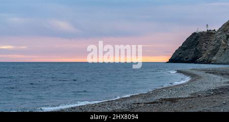Una vista panoramica della spiaggia di la Chucha e il faro di Cabo Sacratif in Andalusia a asunset Foto Stock