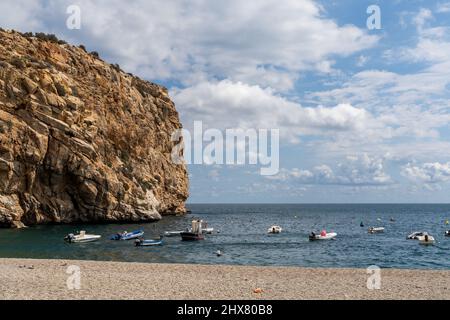 molte piccole barche colorate di legno da pesca ancorate in acque turchesi con una scogliera di arenaria alle spalle Foto Stock