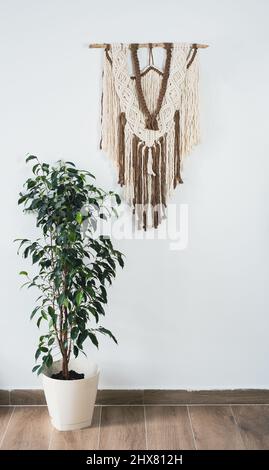 Pannello a parete in stile Boho realizzato con fili di cotone di colore naturale utilizzando la tecnica macrama per l'arredamento della casa. Foto Stock