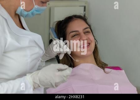 Ragazza adolescente sorridente con i bretelle che hanno trattamento dentale all'ufficio del dentista Foto Stock