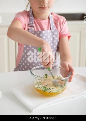 Zucchine Frittata - uova sbattute di ÔøΩCombining, parmigiano vegetariano e menta in un recipiente per la miscelazione (passaggio 4 di 6) Foto Stock