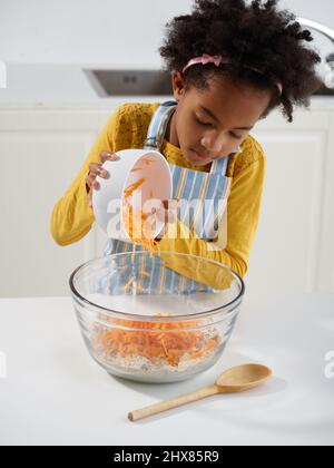 Muffin alla carota e all'arancia - combinazione degli ingredienti secchi in un recipiente per la miscelazione (passaggio 1 di 4) Foto Stock