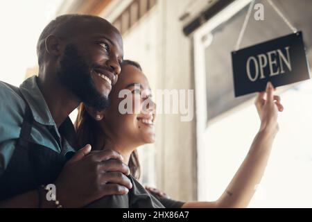 Siamo stati in per una giornata piena di impegni, babe. Scatto di una giovane coppia in piedi insieme e girare il cartello sulla porta per il loro negozio di biciclette. Foto Stock