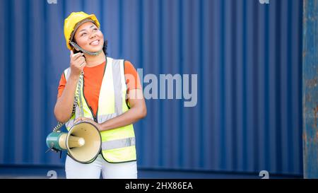 Donna afroamericana vestito logistico comunica urlando forte tenendo un megafono per magazzino o attività logistica, esprimendo il successo e. Foto Stock