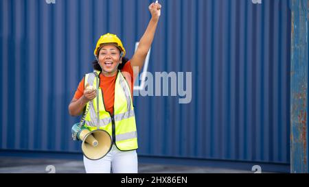 Donna afroamericana vestito logistico comunica urlando forte tenendo un megafono per magazzino o attività logistica, esprimendo il successo e. Foto Stock