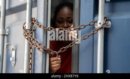 Donna intrappolata nel contenitore di carico aspetta per il traffico di esseri umani o lavoratori di fronte, donna che tiene la chiave maestra aspetta per l'aiuto holp Foto Stock