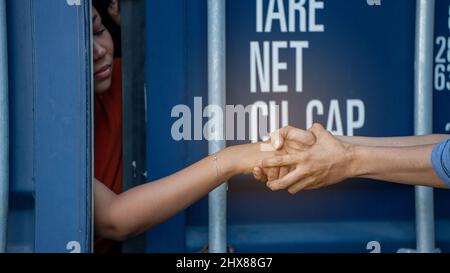 Donna intrappolata nel contenitore di carico aspetta per il traffico di esseri umani o lavoratori di fronte, donna che tiene la chiave maestra aspetta per l'aiuto holp Foto Stock