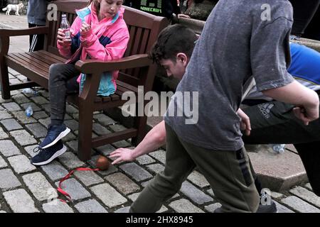 Jedburgh, giovedì 10 marzo 2022. Un ragazzo si avvicina per il Ba, mentre una giovane ragazza guarda avanti durante l'evento annuale 'Fastern Eve Handba' in High Street di Jedburgh, nei confini scozzesi, il 10 marzo 2022 a Jedburgh, Scozia. L'evento annuale, iniziato nel 1700, si svolge oggi e coinvolge due squadre, gli Uppies (residenti dalla parte più alta di Jedburgh) e i Doonies (residenti dalla parte più bassa di Jedburgh) che ottengono la palla alla parte superiore o inferiore della città. La palla, che è in pelle, farcita di paglia e decorata con nastri, è gettata nella folla per implorare Foto Stock