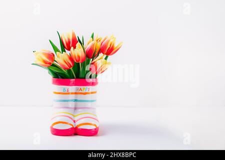 Coloratissimi tulipani freschi primavera fiori in vaso stivali su sfondo bianco isolato. Primavera, giornata della donna, 8 marzo, felice compleanno concetto. Messa a fuoco selettiva Foto Stock