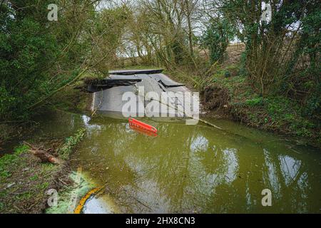 Un'alluvione nella base di una strada sunken in mezzo a asfalto rotto su una sezione del B4069 vicino Lyneham nel Wiltshire, che è ancora in movimento e in evoluzione, a seguito di una sfila di terra nel mese di febbraio. Data foto: Giovedì 10 marzo 2022. Foto Stock
