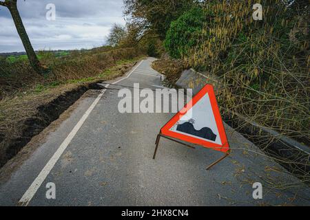 Un adesivo per skateboard su un cartello che indica le cime sulla strada è visto su una sezione gravemente danneggiata del B4069 vicino Lyneham nel Wiltshire, che è ancora in movimento e cambia forma, a seguito di una striscia di terra nel mese di febbraio. Data foto: Giovedì 10 marzo 2022. Foto Stock