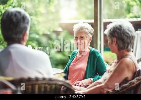 Buoni vecchi amici che si riuniscono per bere. Scatto ritagliato di un gruppo di amici anziani che si godono una data pranzo. Foto Stock