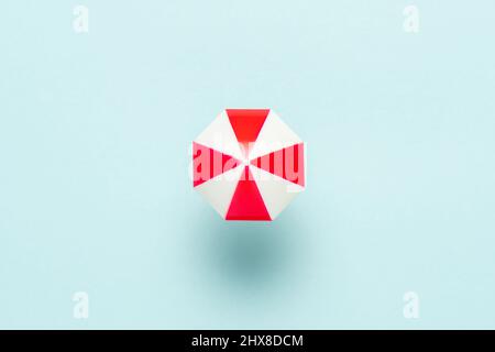 Minimal concetto estivo con ombrello su sfondo blu. Appartamento vacanza sfondo laici. Foto Stock