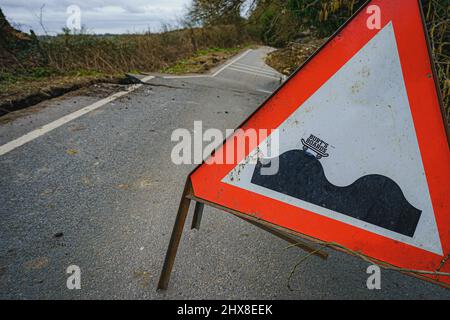 Un adesivo per skateboard su un cartello che indica le cime sulla strada è visto su una sezione gravemente danneggiata del B4069 vicino Lyneham nel Wiltshire, che è ancora in movimento e cambia forma, a seguito di una striscia di terra nel mese di febbraio. Data foto: Giovedì 10 marzo 2022. Foto Stock