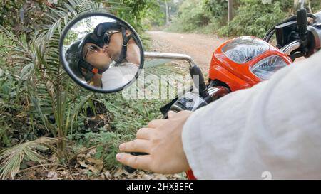 Coppia d'amore su moto rossa in abiti bianchi per andare sulla strada forestale viaggio. Vista nel retrovisore. Due turisti caucasici uomo guida Foto Stock