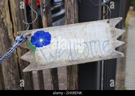 Cartello di benvenuto in legno resistente agli agenti atmosferici appeso su una recinzione Foto Stock