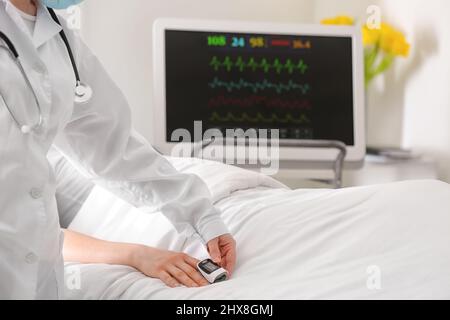 Medico che misura il livello di saturazione di ossigeno del sangue del paziente in clinica Foto Stock