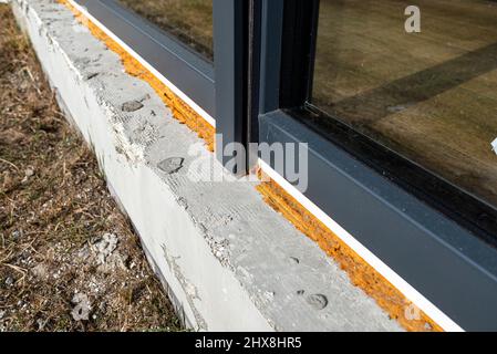 Vecchia schiuma di montaggio gialla sotto una grande finestra terrazza, visibile styrofoam che isola le fondamenta della casa. Foto Stock
