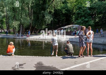 KHARKIV, UCRAINA - 3 AGOSTO 2021: Le persone non identificate partecipano ad un'attrazione per catturare i pesci in uno stagno artificiale nel parco di Sarzhin Yar. Foto Stock