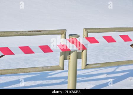 Recinzione metallica con nastro di recinzione rosso e bianco allungato Foto Stock