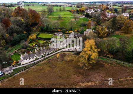 Un'insolita vista dall'alto di questa famosa e molto visitata fila di case del Cotswold, incorniciata da alberi autunnali. Foto Stock