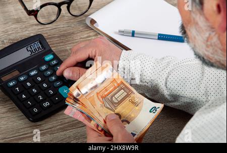 Gestione finanziaria personale, concetto contabile. L'uomo esegue calcoli di operazioni aritmetiche dei costi mensili, controlla le spese. Foto Stock