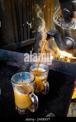 Preparare il tè, una tazza di tè nero appena fatto. Versare il tè nella tazza di vetro. Il tempo della pausa tè. Foto Stock