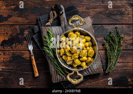 Olive turche grigliate con olio d'oliva ed erbe in padella. Sfondo in legno. Vista dall'alto Foto Stock