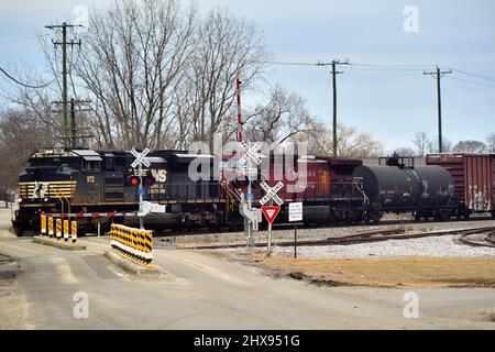 Bartlett, Illinois, Stati Uniti. Un treno merci, guidato da una locomotiva Norfolk Southern Railway, passa attraverso un passaggio di classe. Foto Stock