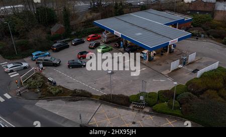 Wigan, Regno Unito: 10 marzo 2022: Vista aerea. Accodando le auto in attesa di acquistare carburante in una stazione di rifornimento di benzina Tesco come i conducenti britannici panico acquistare carburante Foto Stock