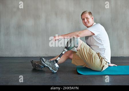 Quando la mente è forte, il corpo segue. Scatto di un amputee giovane che si allenano su un pavimento della palestra. Foto Stock